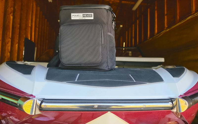 The authentic Dock Father bag is standing on the rear deck of a red-and-white boat inside a wood-lined storage building.